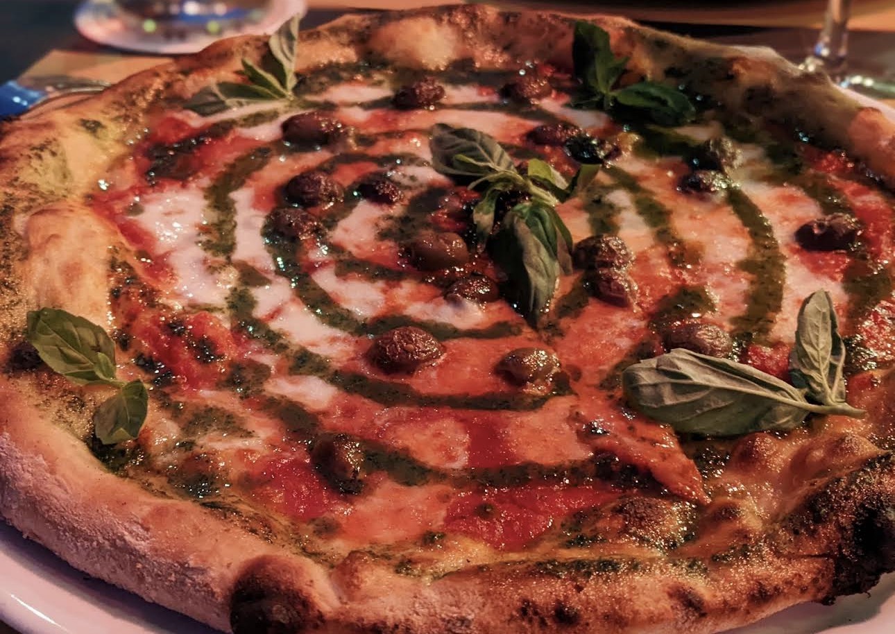Pizza gourmet con pesto, olive taggiasche e basilico fresco