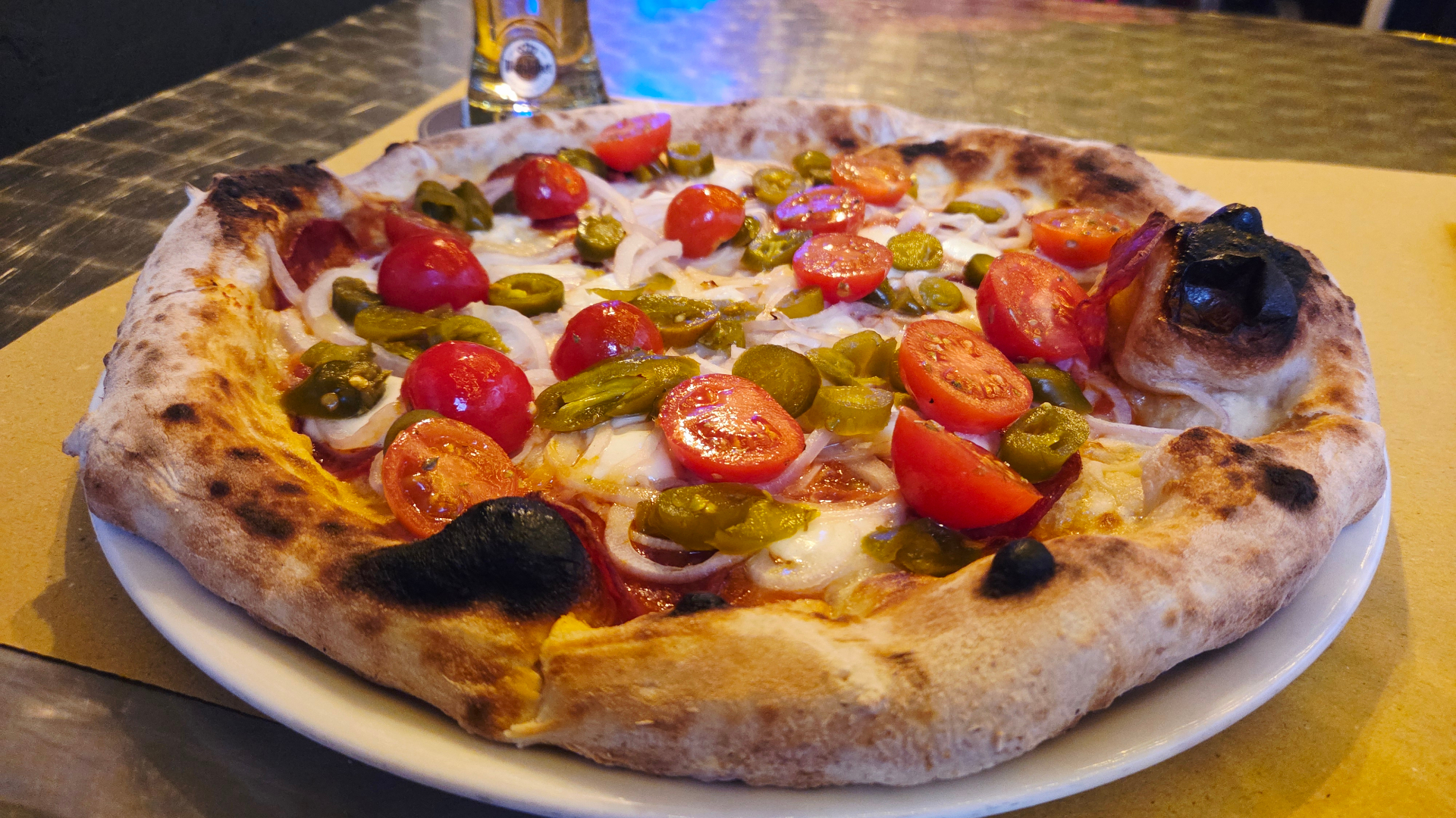 Pizza appena sfornata con pomodorini, jalapeños e cornicione alveolato